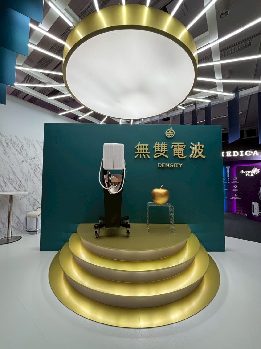 醫美儀器精品級展台設計_無雙電波DENSITY金色環形光帶天花與階梯式台座,提升醫療器材展覽陳列質感